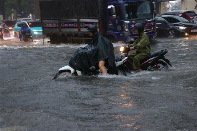 Heavy downpours leave Ha Noi's low-lying streets under water- Ảnh 1.